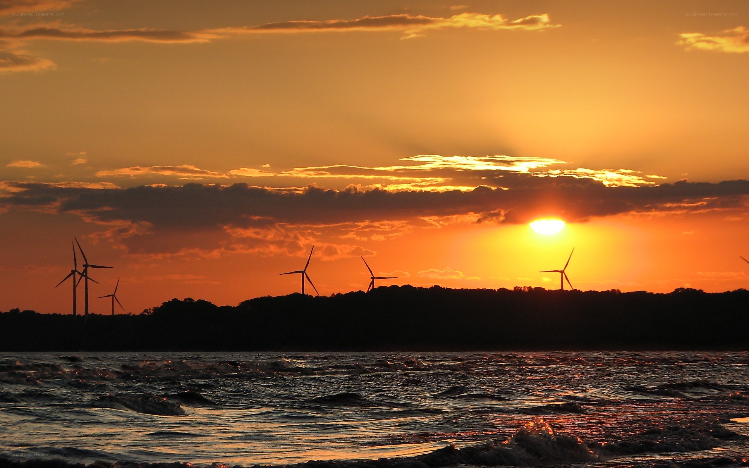 Wind turbines at sunset over water