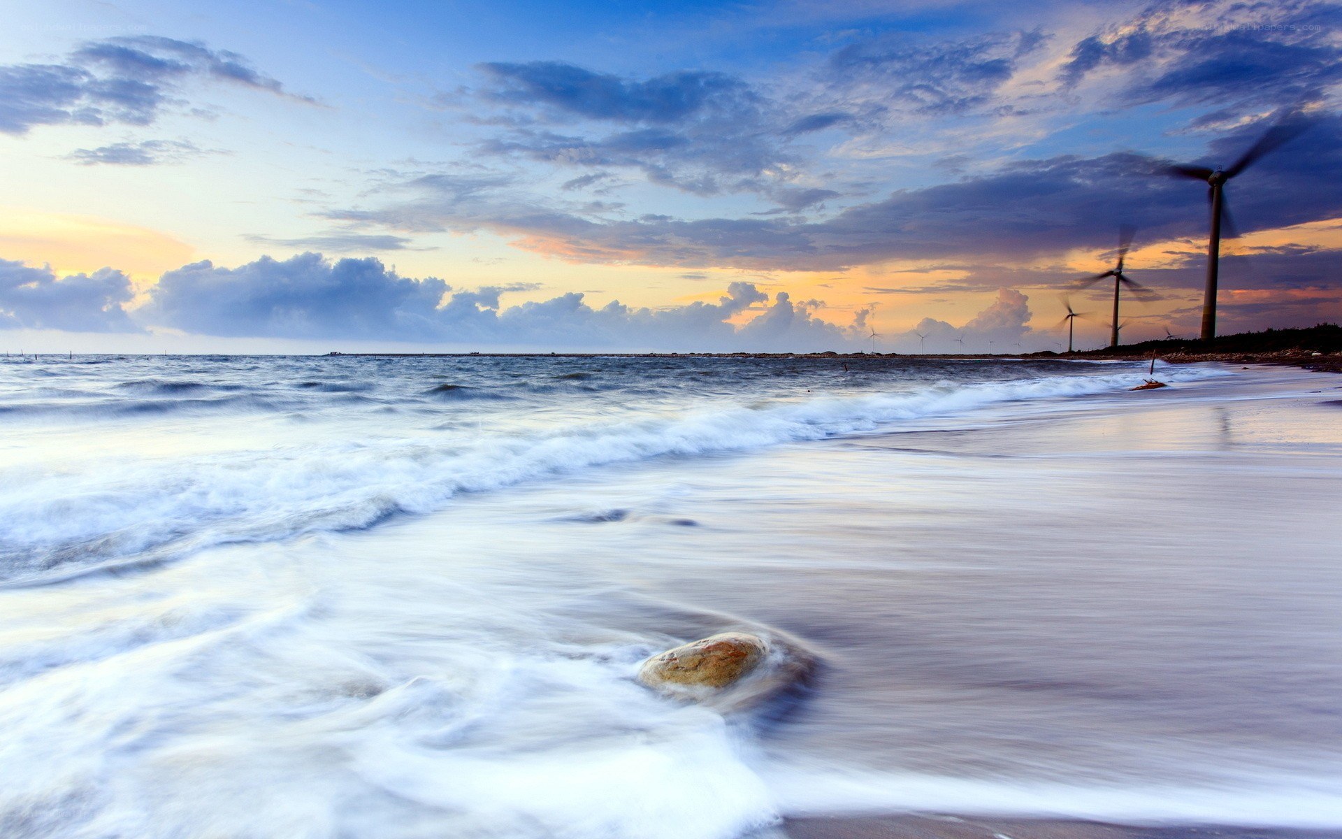 Wind turbines on a beach at sunset