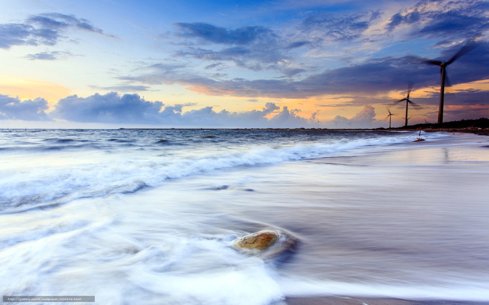 Wind turbines on a beach at sunset