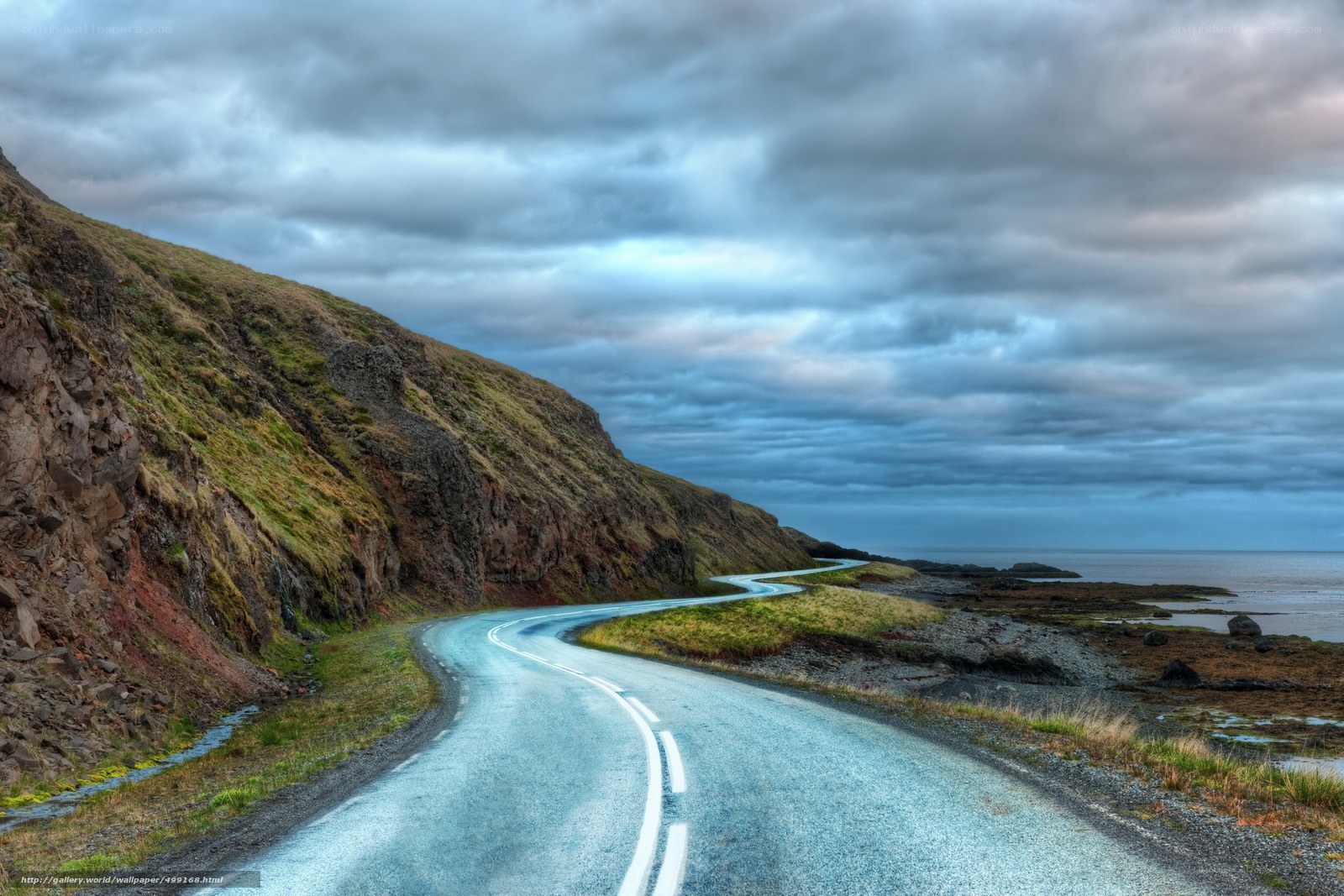 Winding coastal road under cloudy sky