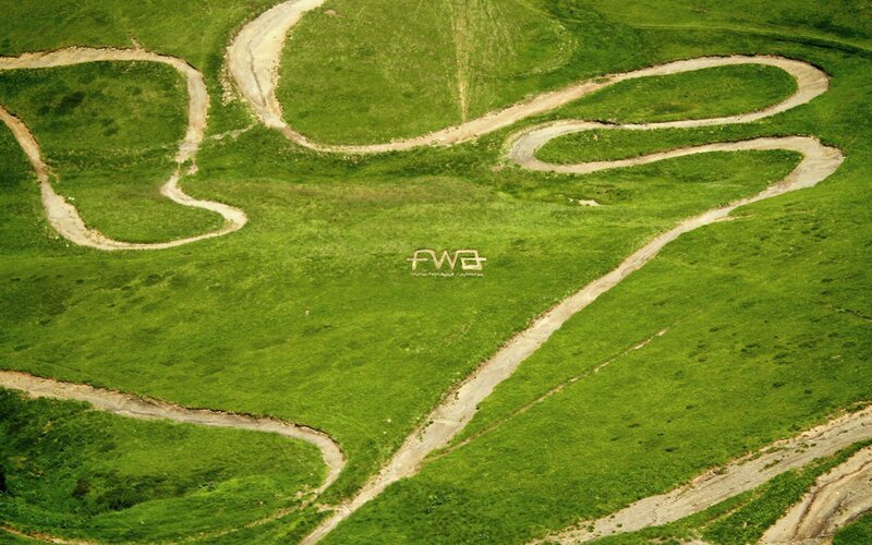 Winding dirt paths on a green hill