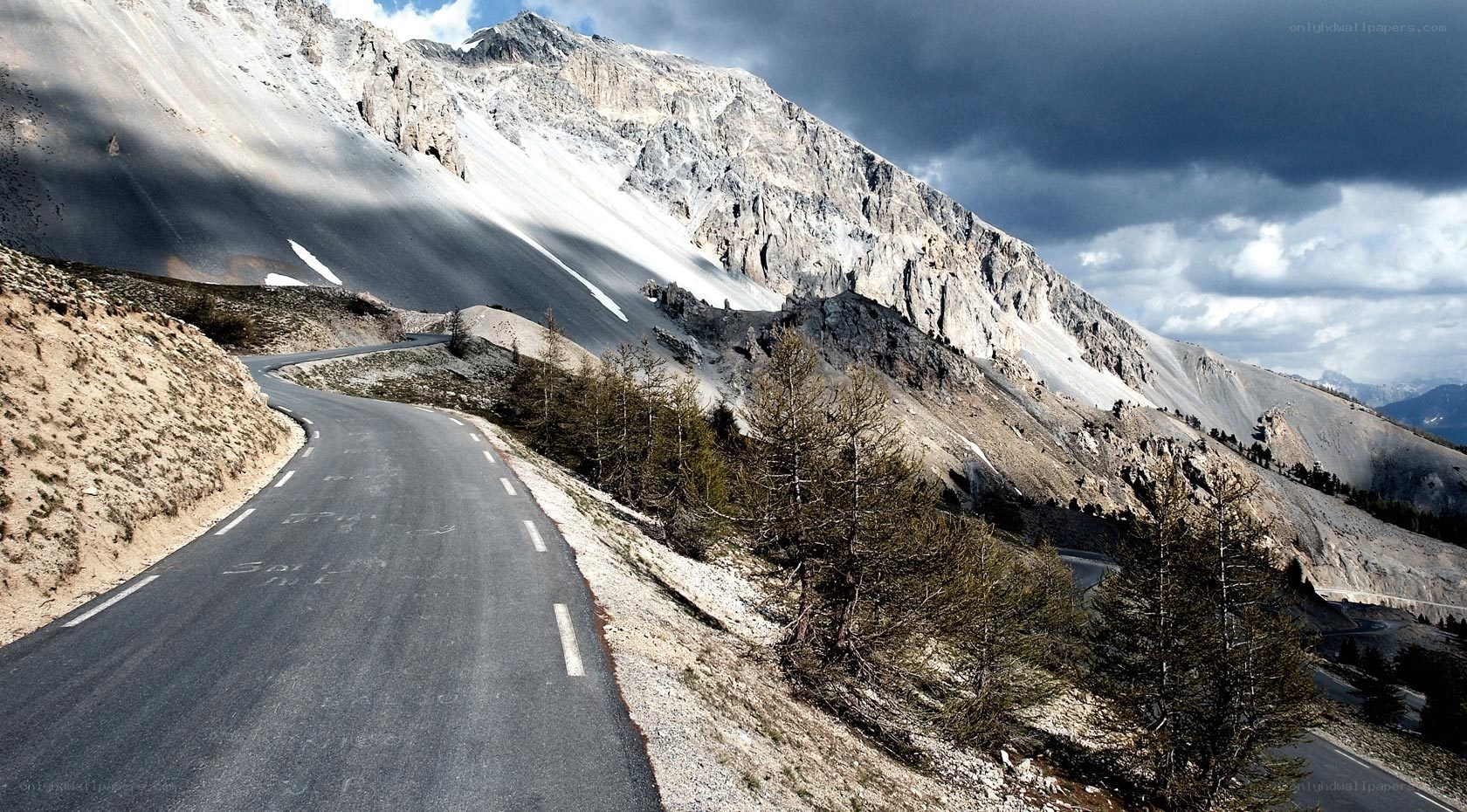 Winding mountain road under stormy sky