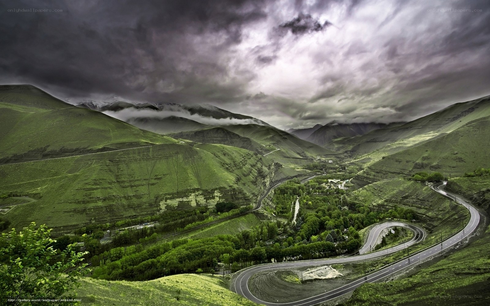 Winding mountain road under stormy sky