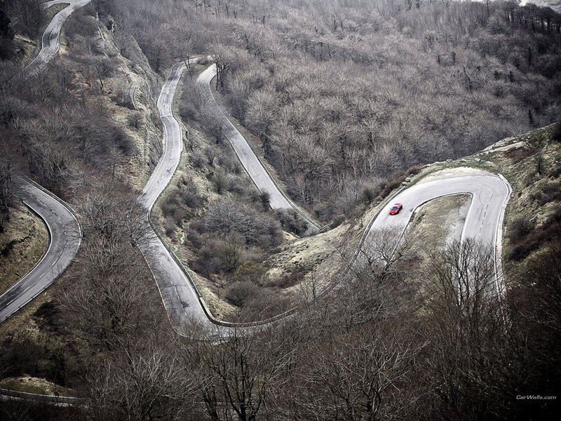 Winding mountain road with red car