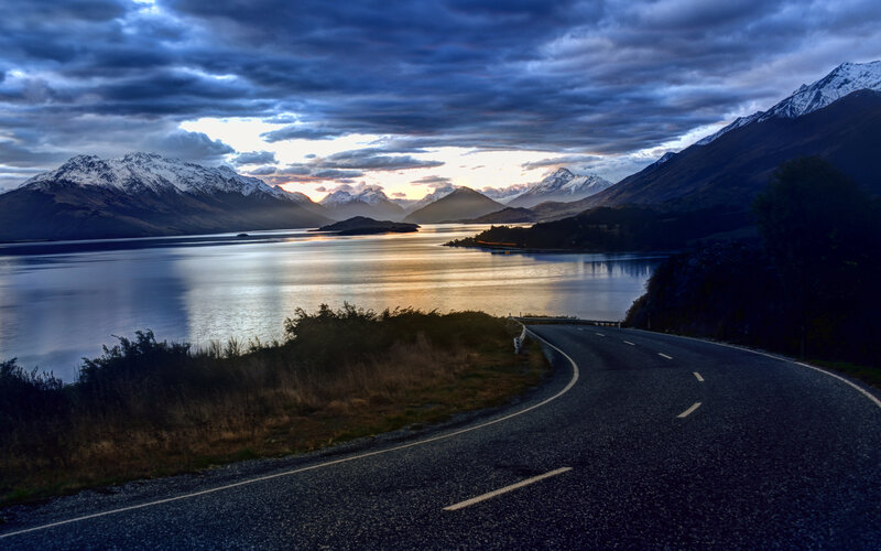 Winding Road by Lake — Blue, Dramatic, Sunset, Photograph, Mountains, Clouds