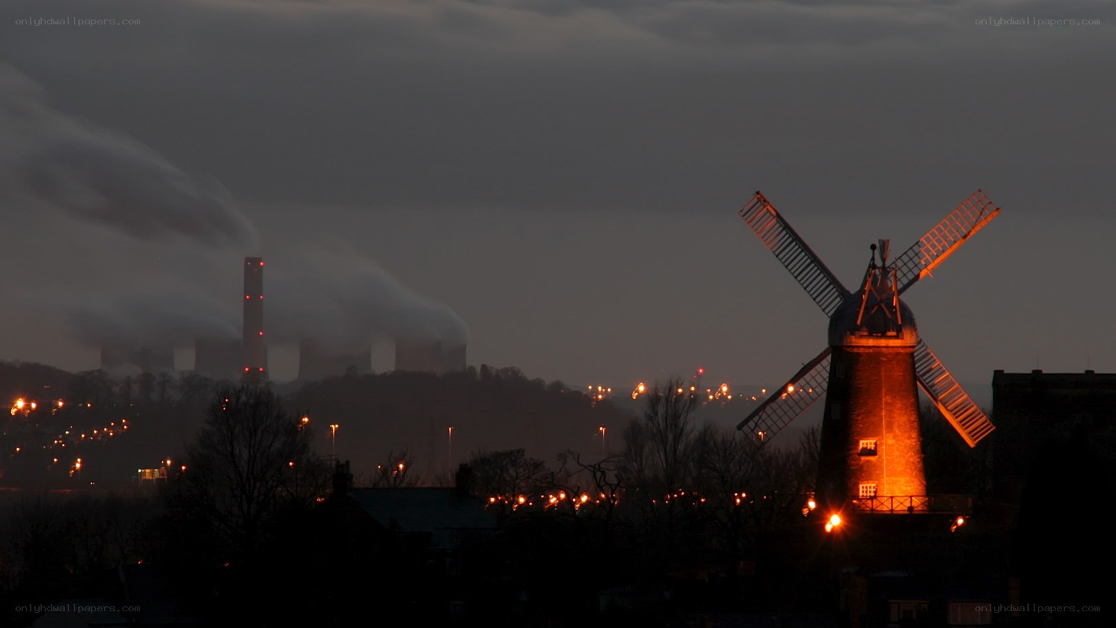 Windmill at dusk with industrial backdrop