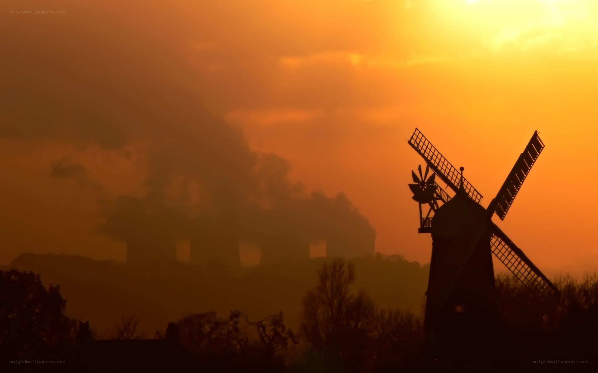 Windmill at sunset with industrial smoke