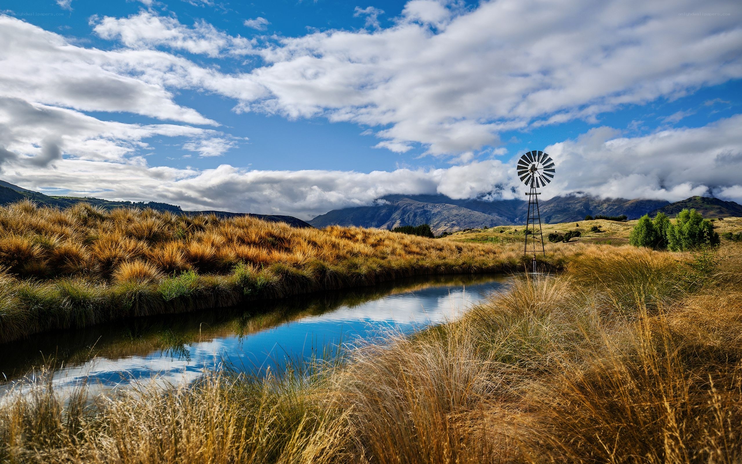 Windmill by a river in the mountains