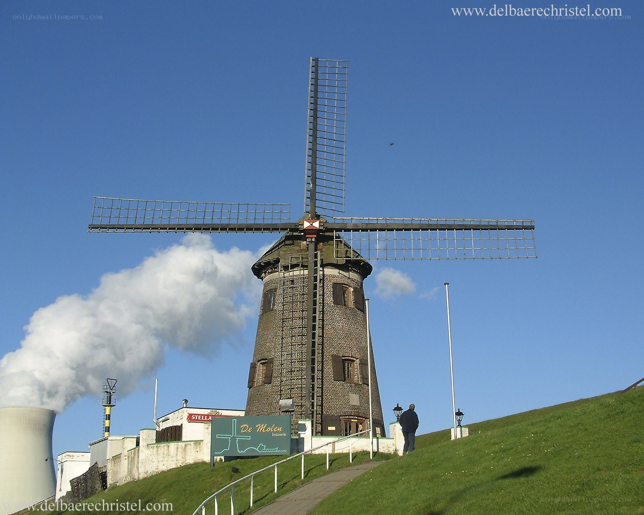 Windmill with smokestack in background