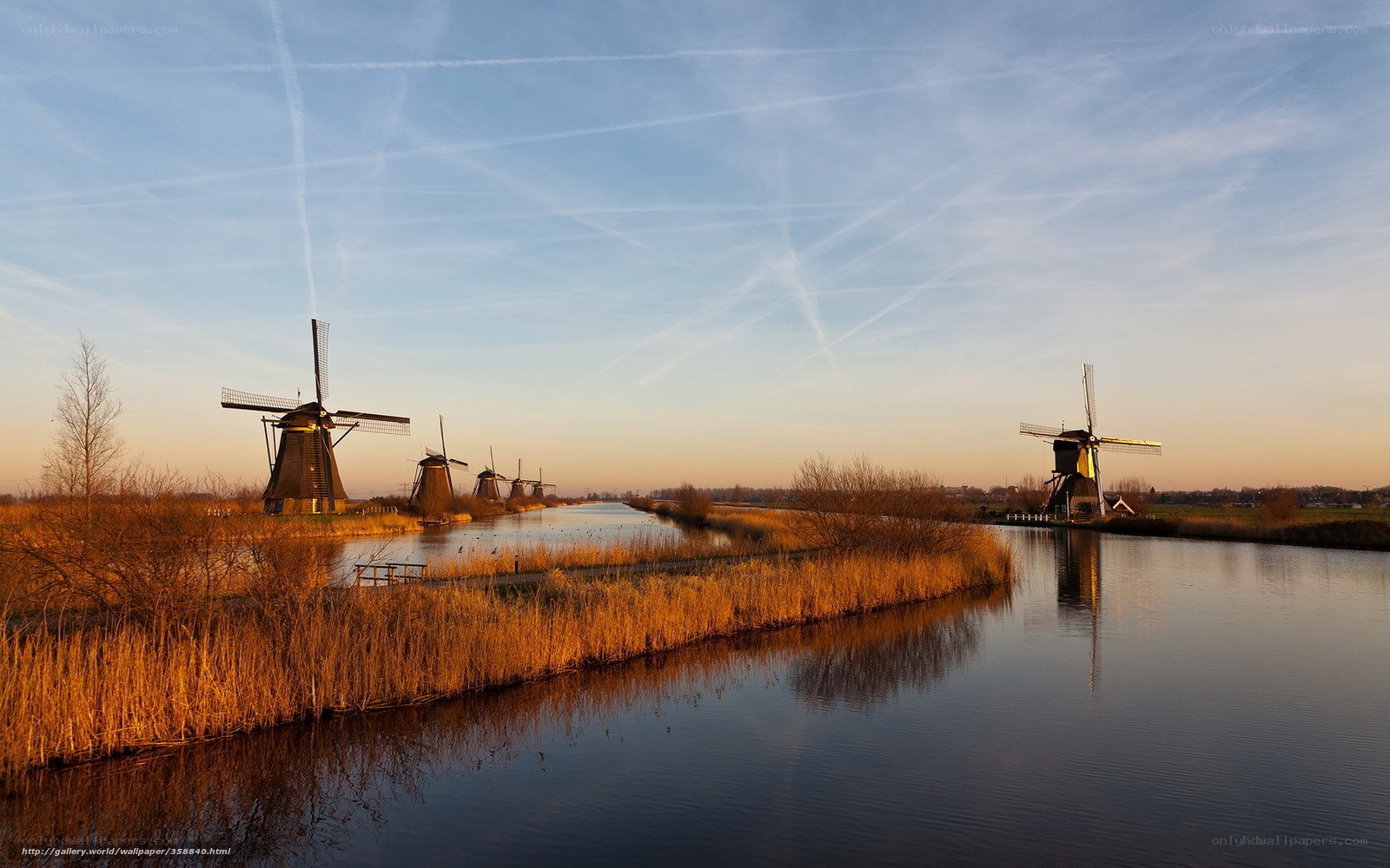 Windmills along a canal at sunset