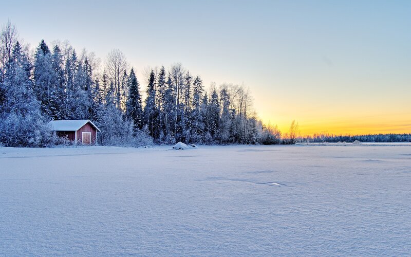 Winter sunset by a red cabin