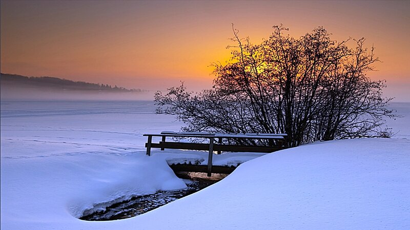 Winter sunset by frozen lake