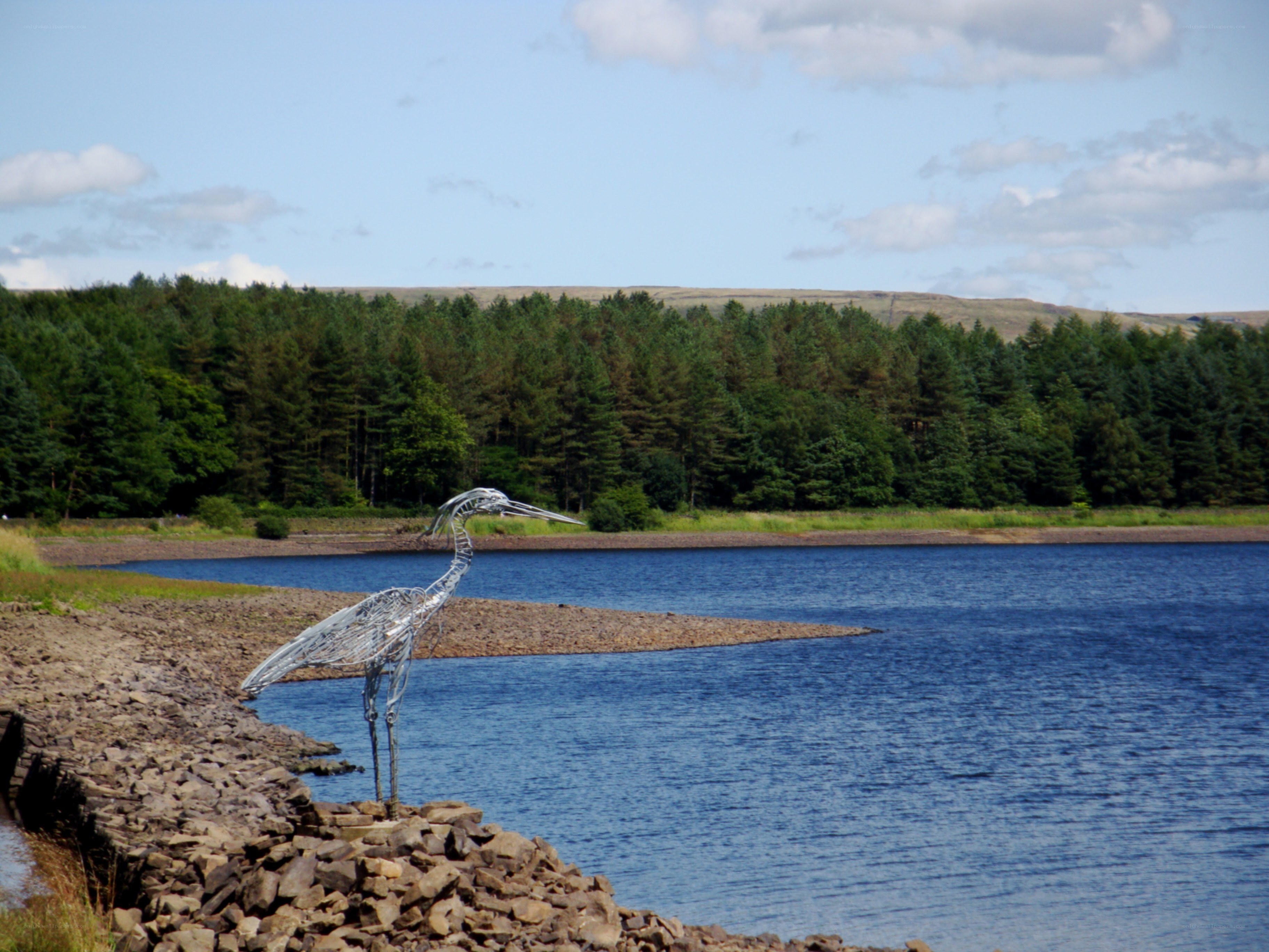 Wire heron sculpture by a lake