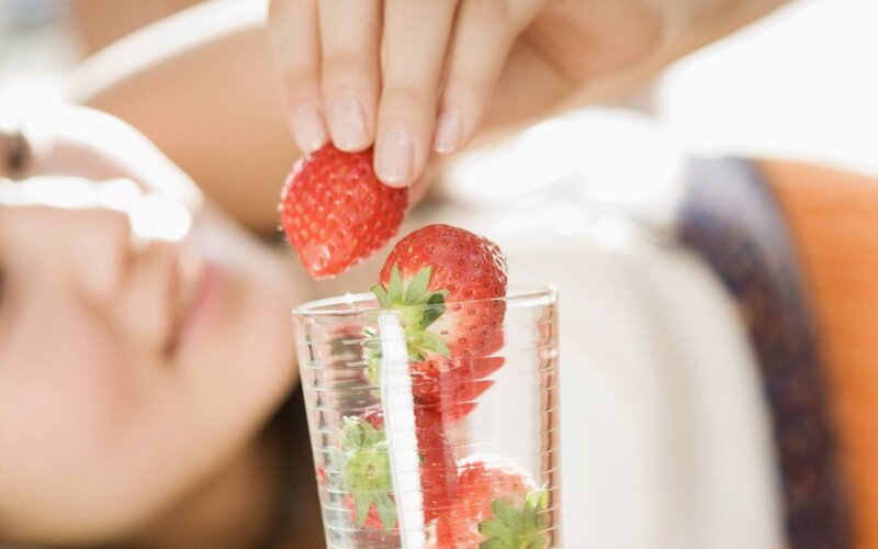 woman adding strawberries to drink