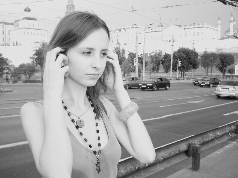 woman adjusting earbuds on street