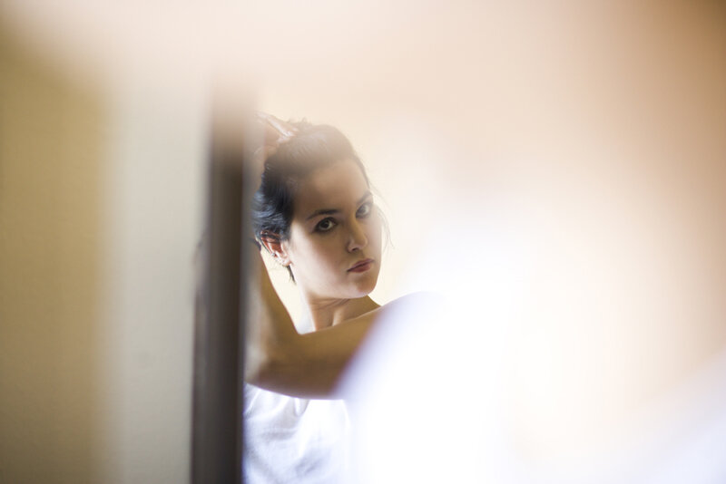 woman adjusting hair in mirror