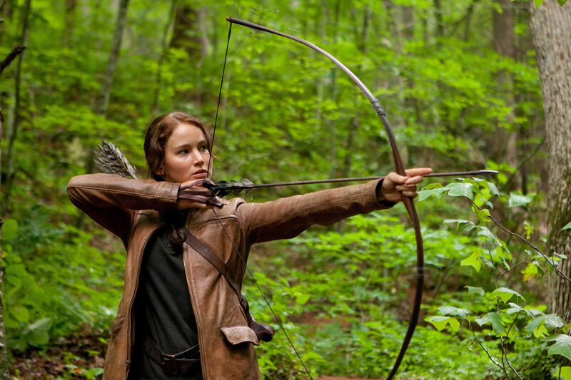woman aiming bow in forest