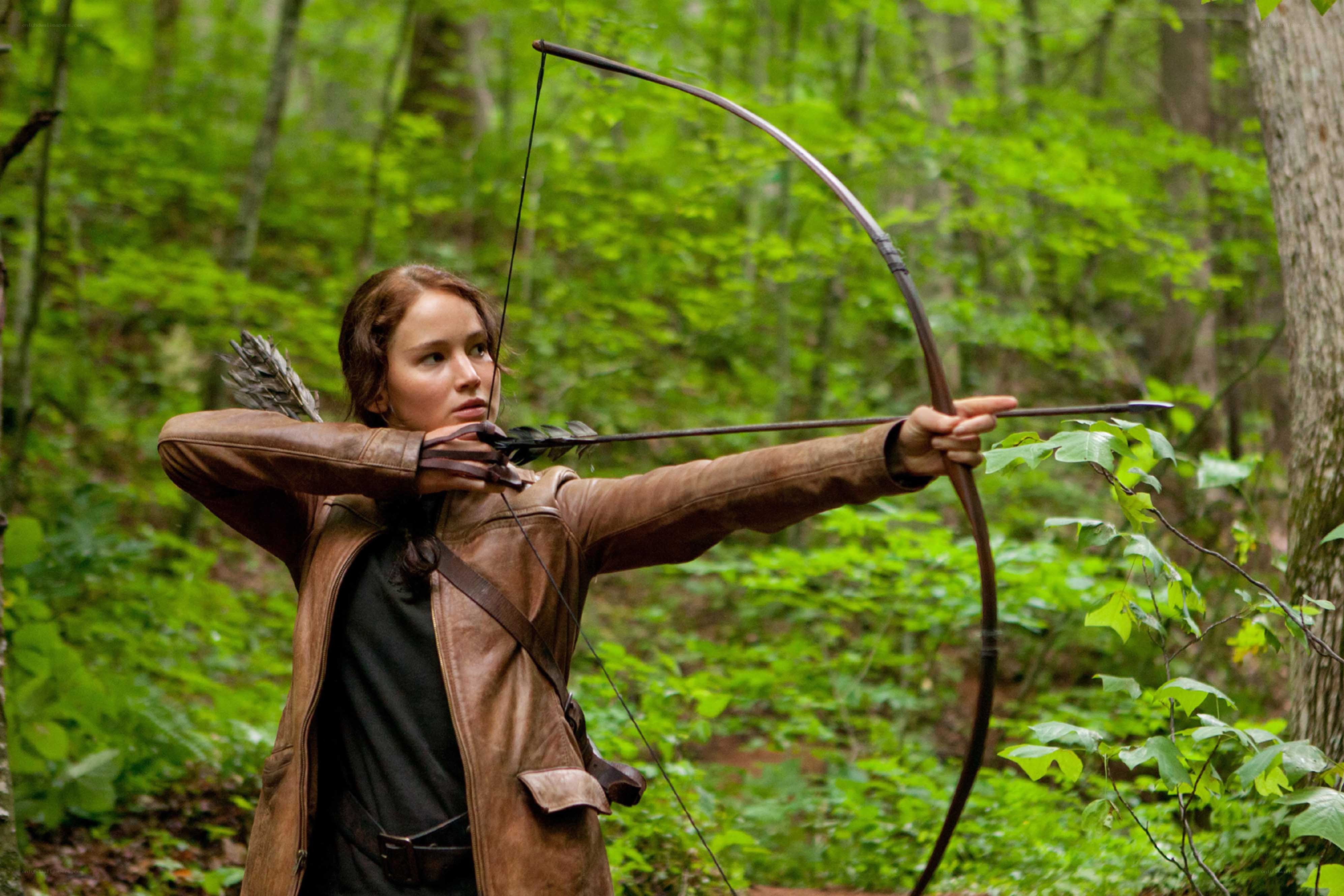 woman aiming bow in forest