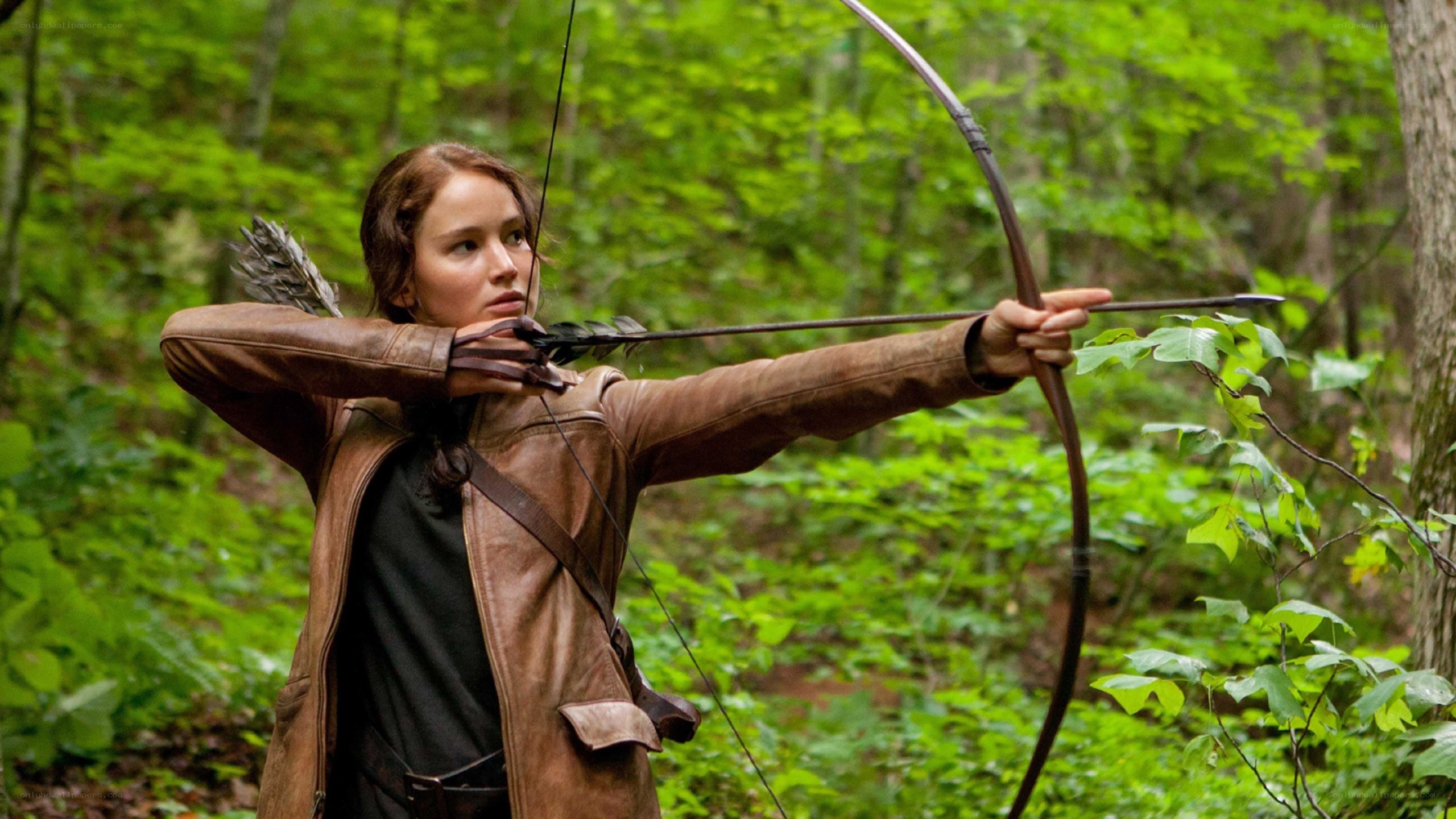woman aiming bow in forest
