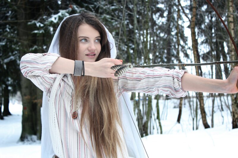 woman aiming bow in winter