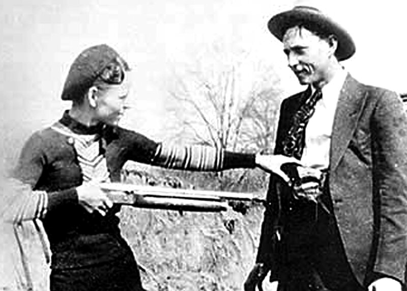Woman aiming rifle at man