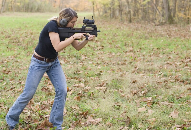 Woman aiming rifle at range