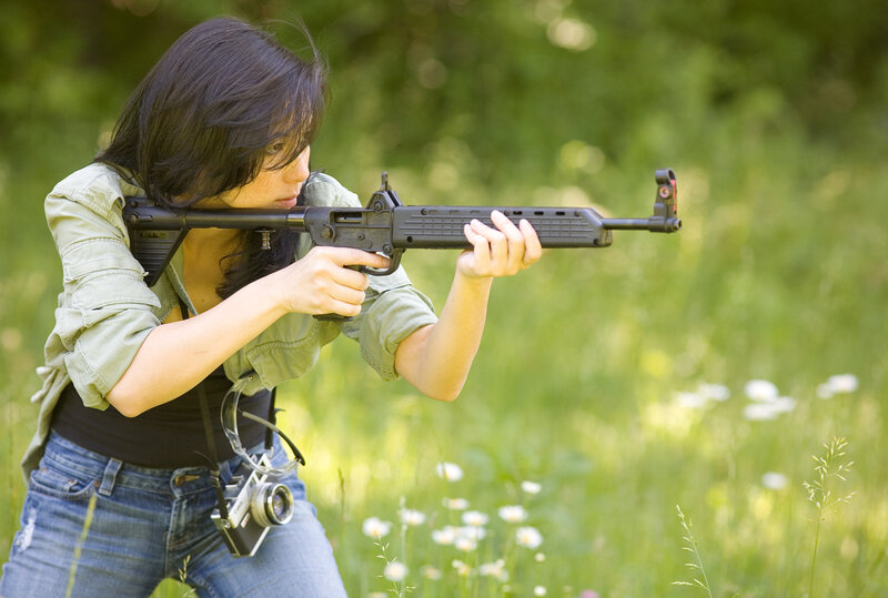 Woman aiming rifle in field