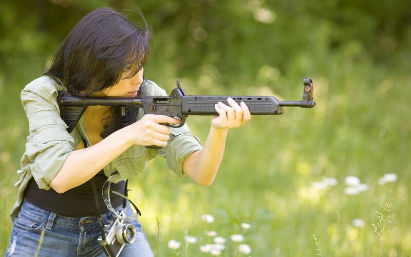 woman aiming rifle in field
