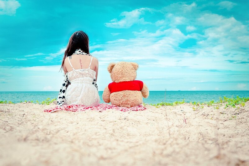 Woman and teddy bear on beach