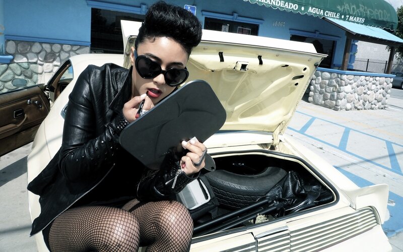 woman applying lipstick in car trunk