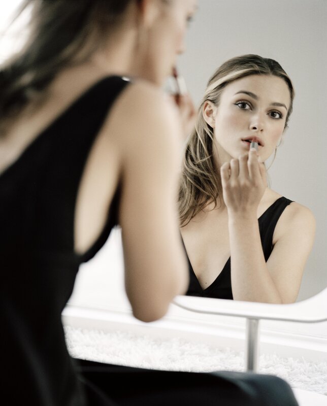 woman applying lipstick in mirror