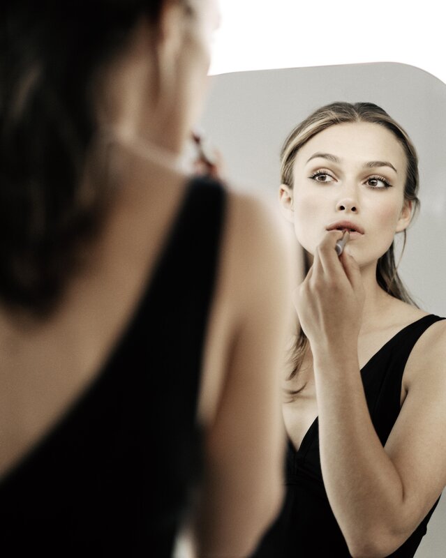 woman applying lipstick in mirror