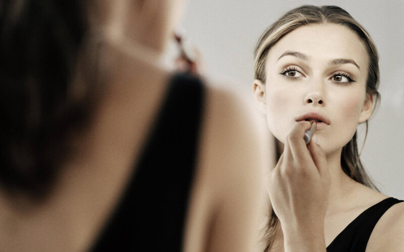 woman applying lipstick in mirror