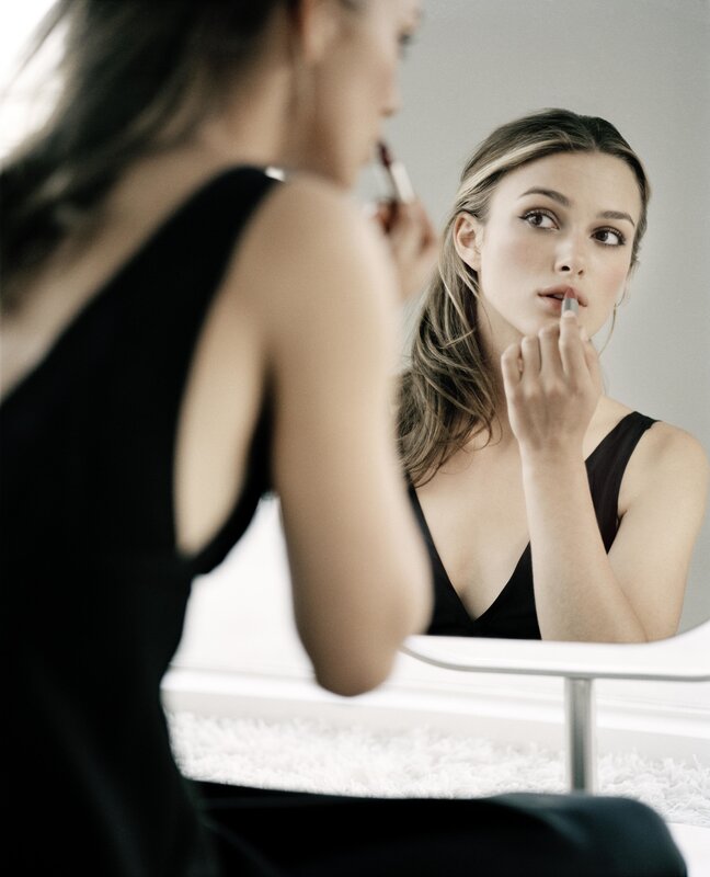 woman applying lipstick in mirror