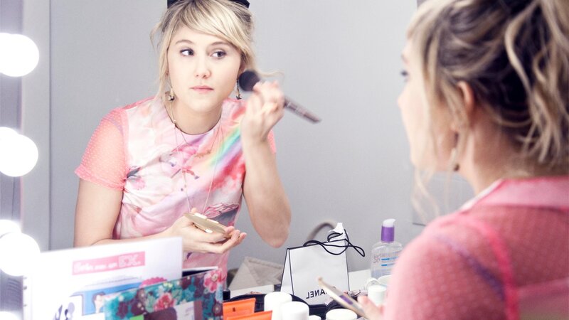 woman applying makeup in front of mirror