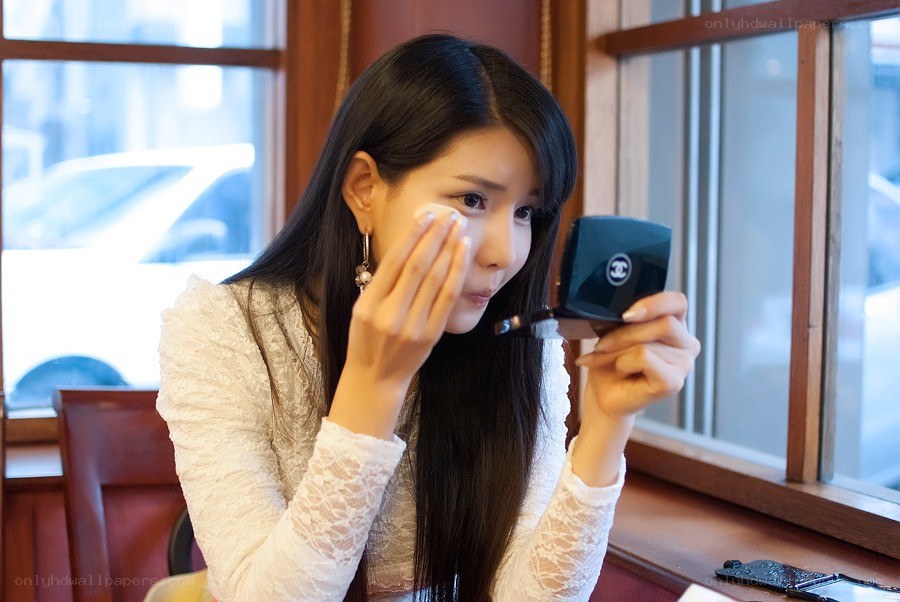 woman applying makeup with compact mirror