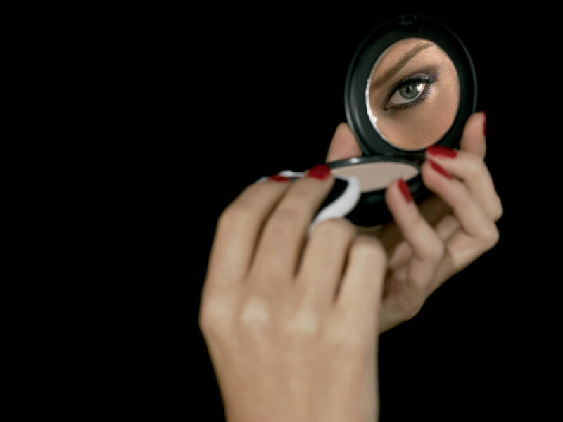 woman applying makeup with compact mirror