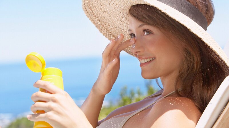 woman applying sunscreen at beach