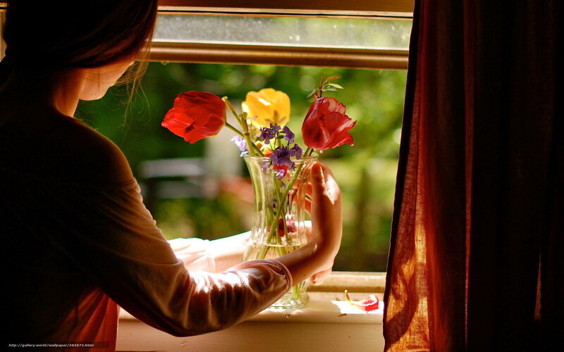 woman arranging flowers by window