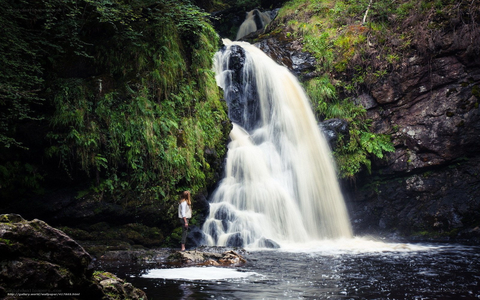 Woman at a forest waterfall
