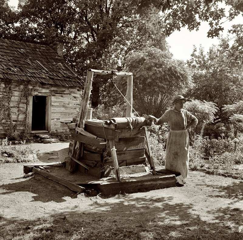 Woman at a hand pump near cabin