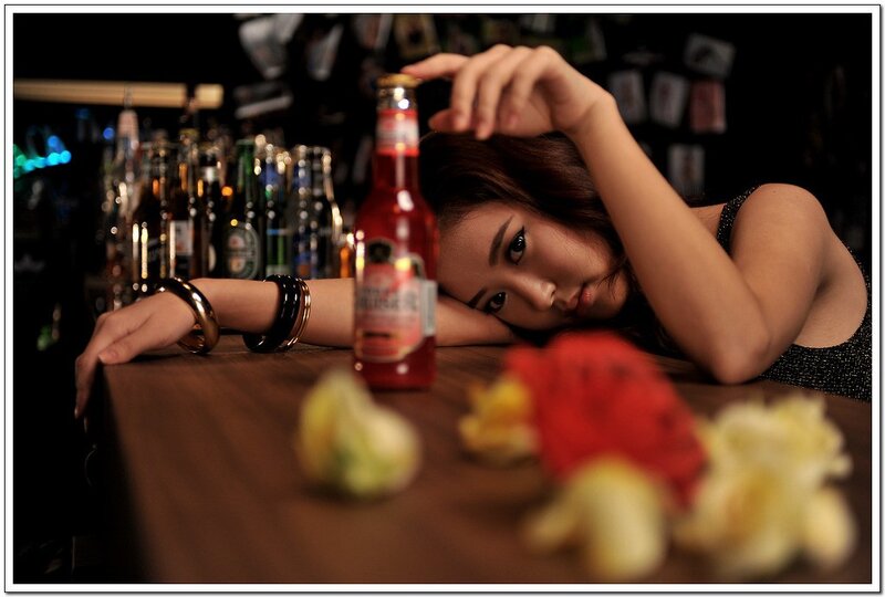 woman at bar with beer bottle