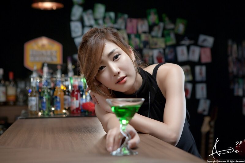 woman at bar with green drink