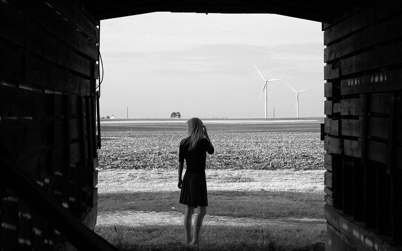 Woman at barn door with wind turbines