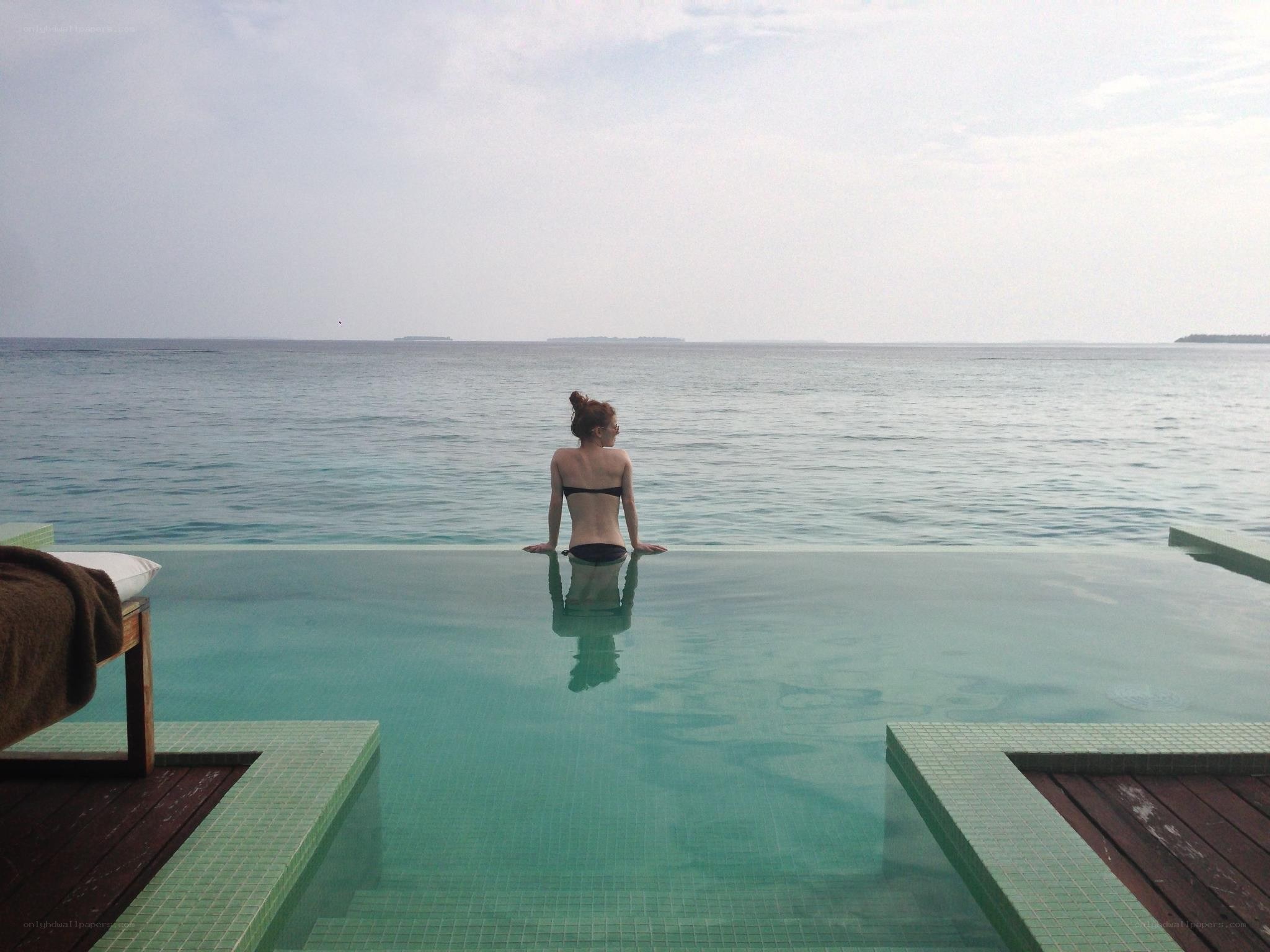 Woman at infinity pool overlooking ocean
