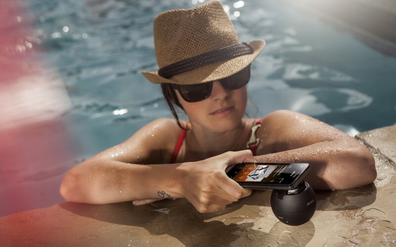 woman at pool with phone and speaker