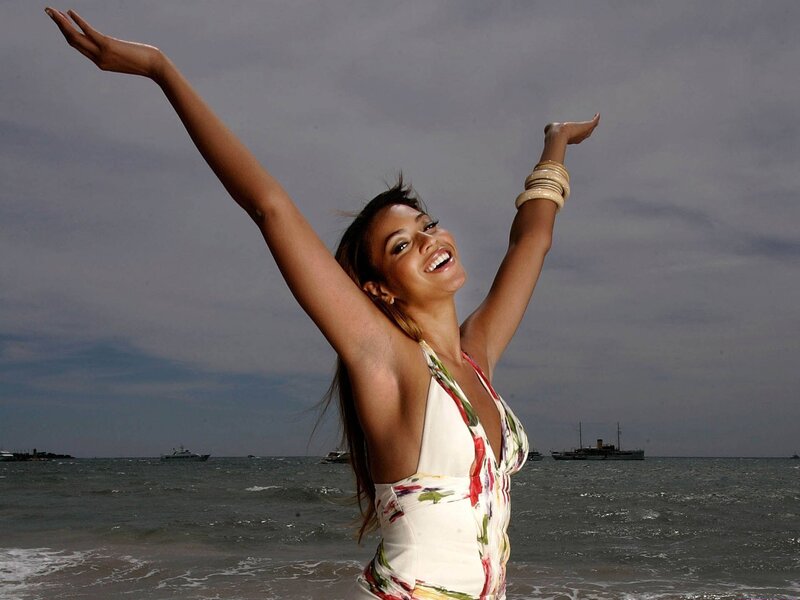 woman at the beach with arms raised