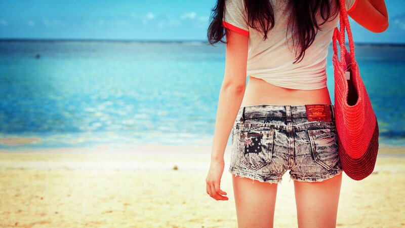 Woman at the beach with red bag