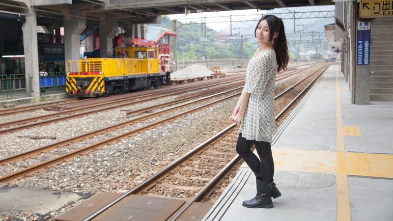 Woman at train station with yellow locomotive