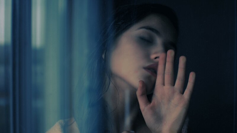 woman at window with hand on glass